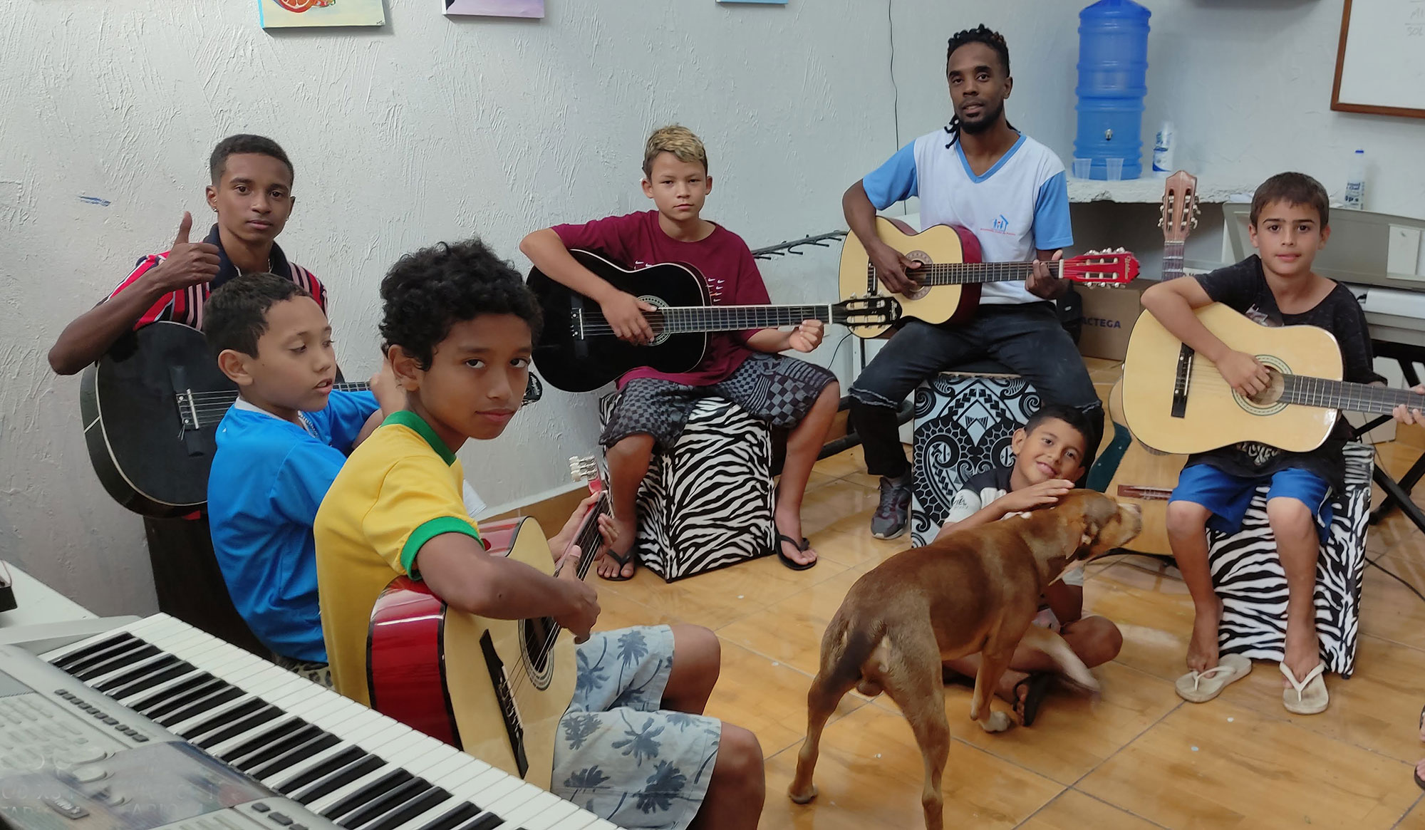 foto-das-crianças-tocando-violão-uma-delas-brincando-com-cachorro-no-centro-da-foto