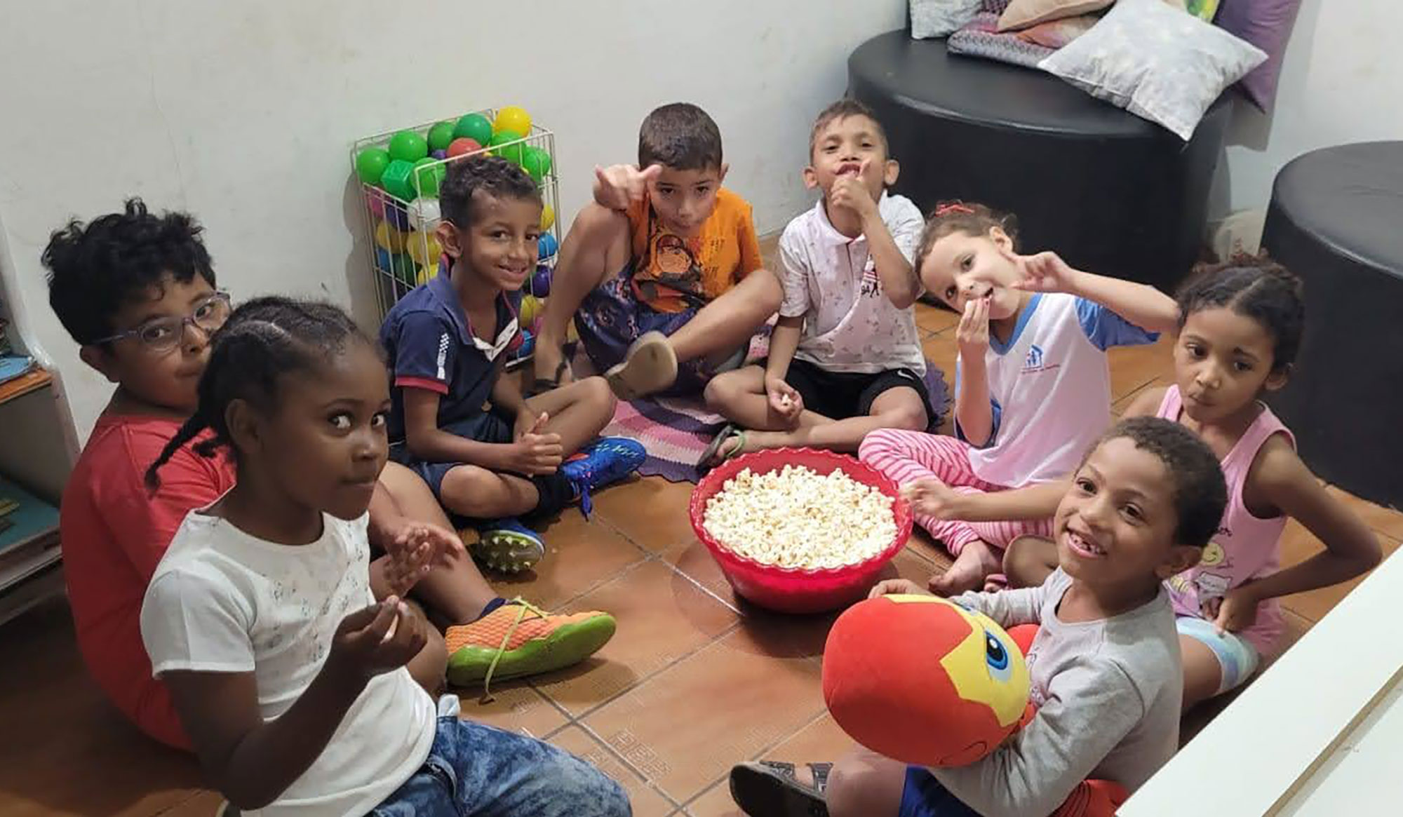 crianças-fazendo-pose-para-foto-durante-aula-do-clubinho-do-saber-com-bacia-de-pipoca-ao-centro